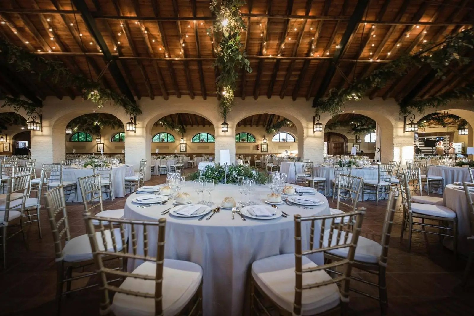 The hall with its arches, iron lamps and a table laid